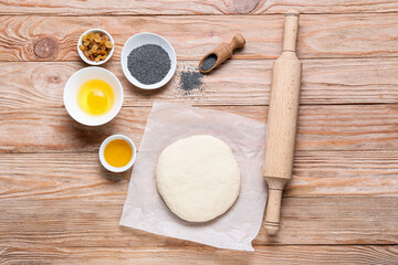 Fresh dough for poppy seed bun and ingredients on wooden background