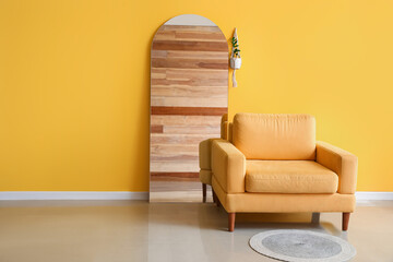 Comfy armchair near stylish mirror in interior of living room