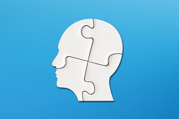 Head made of white jigsaw puzzle four pieces on blue background