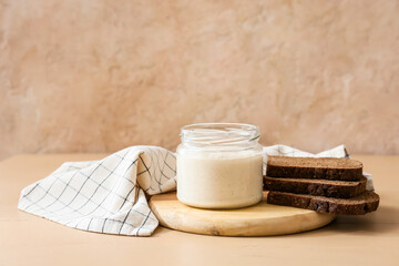Jar with fresh sourdough and bread slices on table