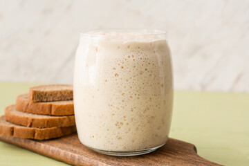 Glass jar with fresh sourdough and bread slices on table