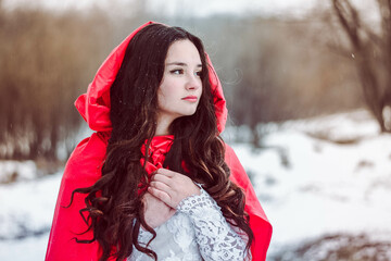 fairy girl red riding hood in the forest in winter in nature in snow