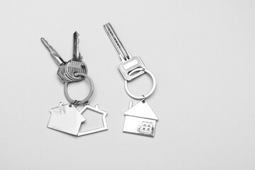 Keys with house shape keychains on grey background