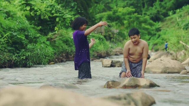 Children playing with friends in the river in countryside, Boys and girls smiling and happiness playing water in the countryside in Thailand.