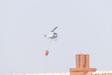 Fire brigade emergency helicopter carrying out a water refuelling flight in an urban area