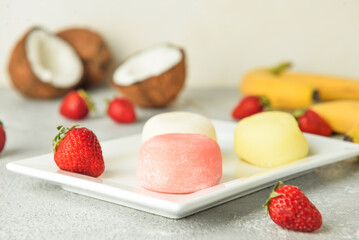 Plate with tasty Japanese mochi and fruits on table
