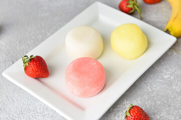 Plate with tasty Japanese mochi and strawberry on light background, closeup