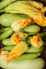 Fresh zucchini with flowers in wicker basket, closeup