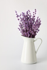 Fototapeta premium Jug with beautiful lavender flowers on grey background