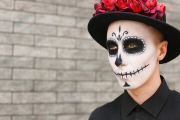 Fototapeta na wymiar Young man with painted skull on his face outdoors. Celebration of Mexico's Day of the Dead (El Dia de Muertos)