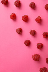 Flat lay composition with red juicy raspberries on a pink background