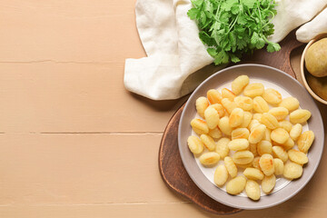 Plate with tasty gnocchi on color wooden background