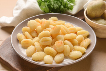 Plate with tasty gnocchi on color wooden background