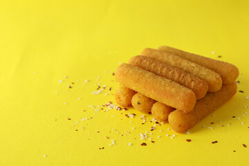 Cheese sticks and spices on yellow background