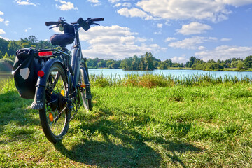 Packed touring bike on a meadow in front of a pond during a bike tour through Germany