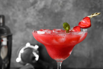 Glass of tasty strawberry margarita on grunge background, closeup