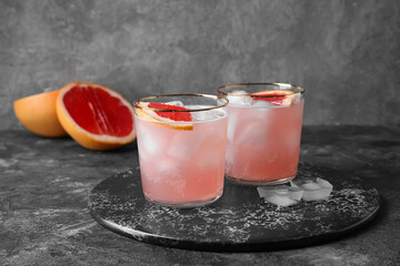 Glasses of tasty grapefruit margarita on grunge background