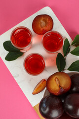 Plum brandy shots and ingredients on pink background