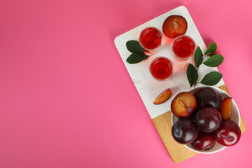 Plum brandy shots and ingredients on pink background