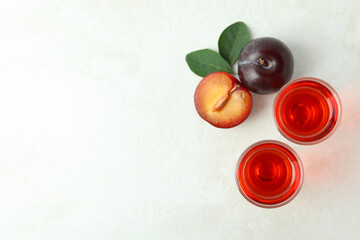 Plum brandy shots and ingredients on white textured table