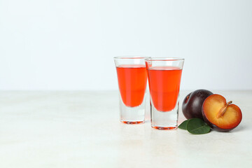 Plum brandy shots and ingredients on white textured table