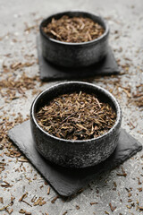 Bowl of dry hojicha green tea on grunge background