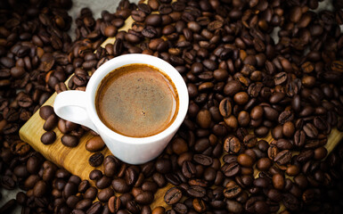 A cup of coffee among coffee beans  on a table
