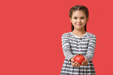 Little girl with pomegranate on color background