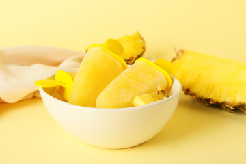 Bowl with tasty pineapple popsicles on color background
