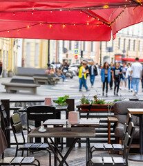 Summer cafe, outdoor tables. Cityscape, sidewalk, passers-by. Photography.