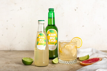 Bottles and glass of tasty kombucha tea with citruses on table
