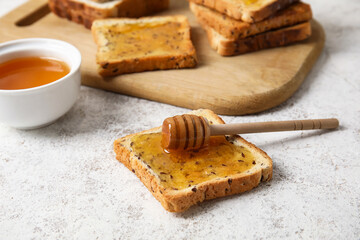 Delicious toasted bread with honey on light background