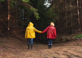 Middle age couple in raincoats walking through forest