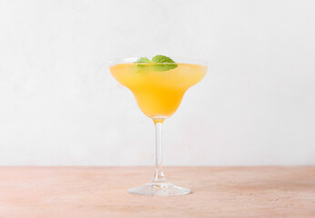 Glass of tasty orange margarita cocktail on light background