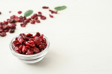 Bowl with tasty dried cranberries on light wooden background, closeup