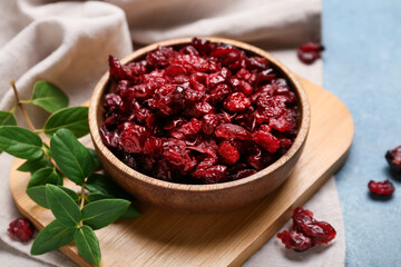 Bowl with tasty dried cranberries on color background, closeup