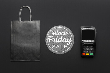 Payment terminal, card with text BLACK FRIDAY SALE and shopping bag on dark background