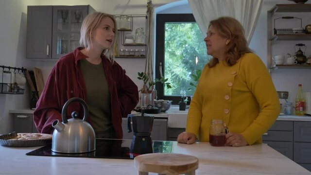 Real mother-in-law with a woman talking in the kitchen in the house