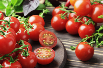 Composition of fresh ripe branches of cherry tomatoes, thyme, basil, rosemary, spices on a wooden textured background