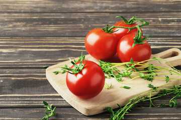 Composition of fresh ripe branches of cherry tomatoes, thyme, basil, rosemary, spices on a wooden textured background