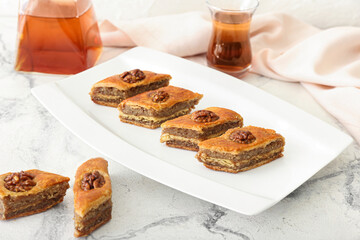 Plate with tasty baklava on light background