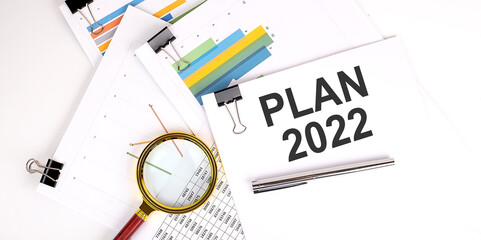 PLAN 2022 text on white paper on the light background with charts paper