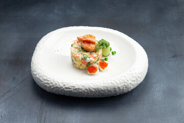 Traditional Russian salad with egg, peas, potatoes and mayonnaise on a plate.