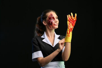 Woman dressed for Halloween as chambermaid with bloodstained rubber gloves on dark background