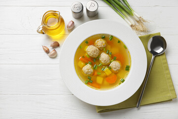 Bowl with tasty meatball soup and spices on light wooden background