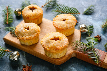Board with tasty mince pies and Christmas decor on color background