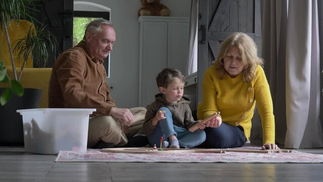 grandparents play the railway with their grandson at home. Video 4K