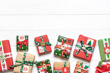 Handmade wrapped red, green gift boxes decorated with ribbons, snowflakes and numbers, Christmas decorations and decor on white table Xmas advent calendar concept Top view Flat lay Holiday card