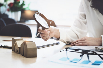 Inspector Concept, a customer is holding a magnifying glass to look at each house model to check...