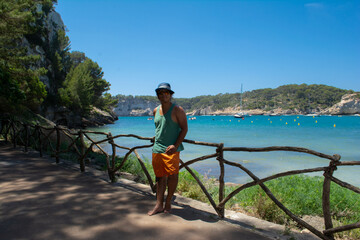 young latino man with blue hat spending his holidays in Menorca looking at the camera, photo located in Balearic Islands, Spain